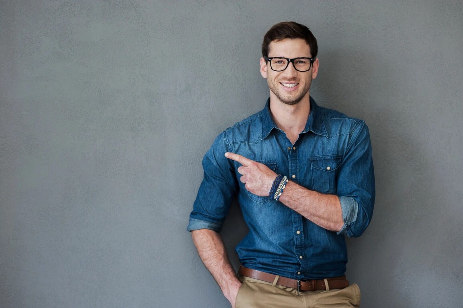 A man in blue shirt and brown pants pointing to the side.